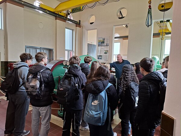 Schülergruppe hört einem Führer in einem Gebäude zu. Gruppe von Schülern bei einer Besichtigung.