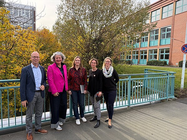 Austauschgespräch zwischen Provadis und Fachverband PlasticsEurope Deutschland Fünf Personen stehen auf einer Brücke des Provadis Campus vor herbstlich gefärbten Bäumen und einem Backsteingebäude. Anlass ist ein Austausch zwischen Provadis und dem Fachverband PlasticsEurope Deutschland